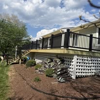 Wood deck with black railings viewed from the landscaped yard