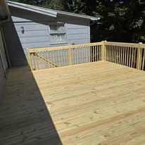 Completed wooden deck with matching wood railing beside a house