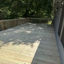 Wood deck in tree shade with railing around the edge