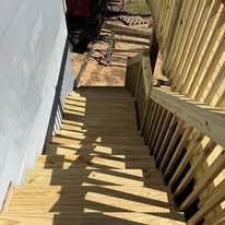 Wood deck stairs with matching railing alongside the house