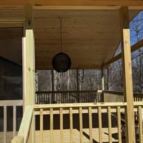 Covered deck with hanging light and wooded view